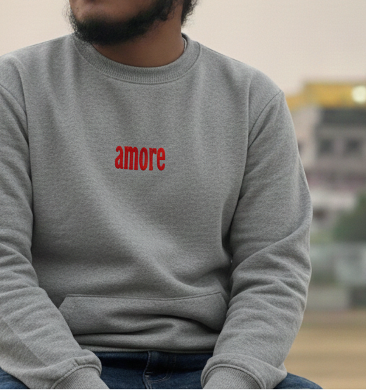 Person wearing a gray sweatshirt with 'amore' text and a red patterned headscarf outdoors.