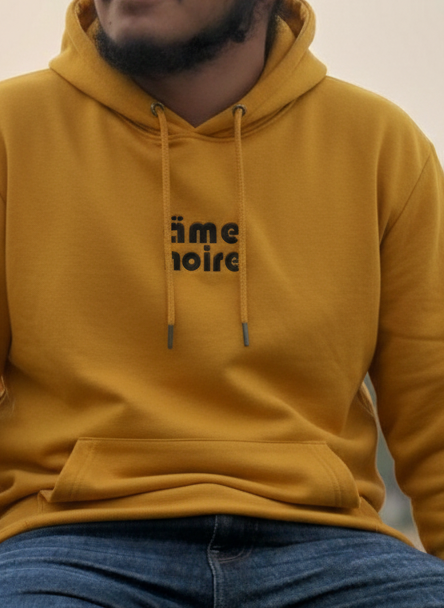 Person wearing a mustard yellow hoodie and red headscarf sitting outdoors.
